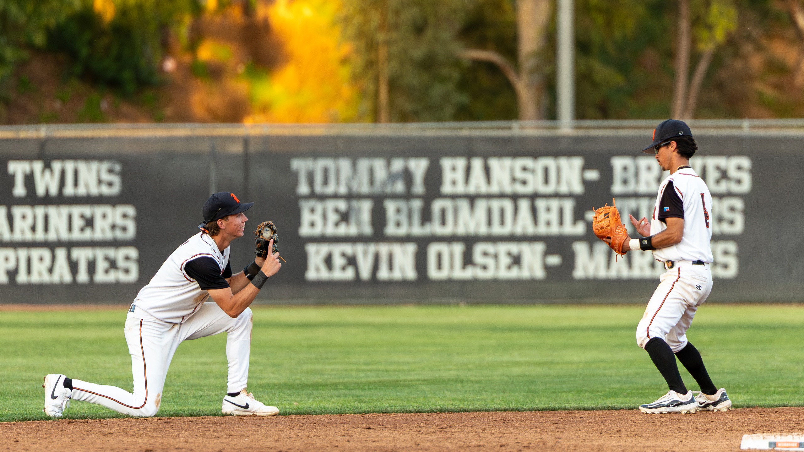 Two baseball players celebrate a big play by pretending to take a picture together
