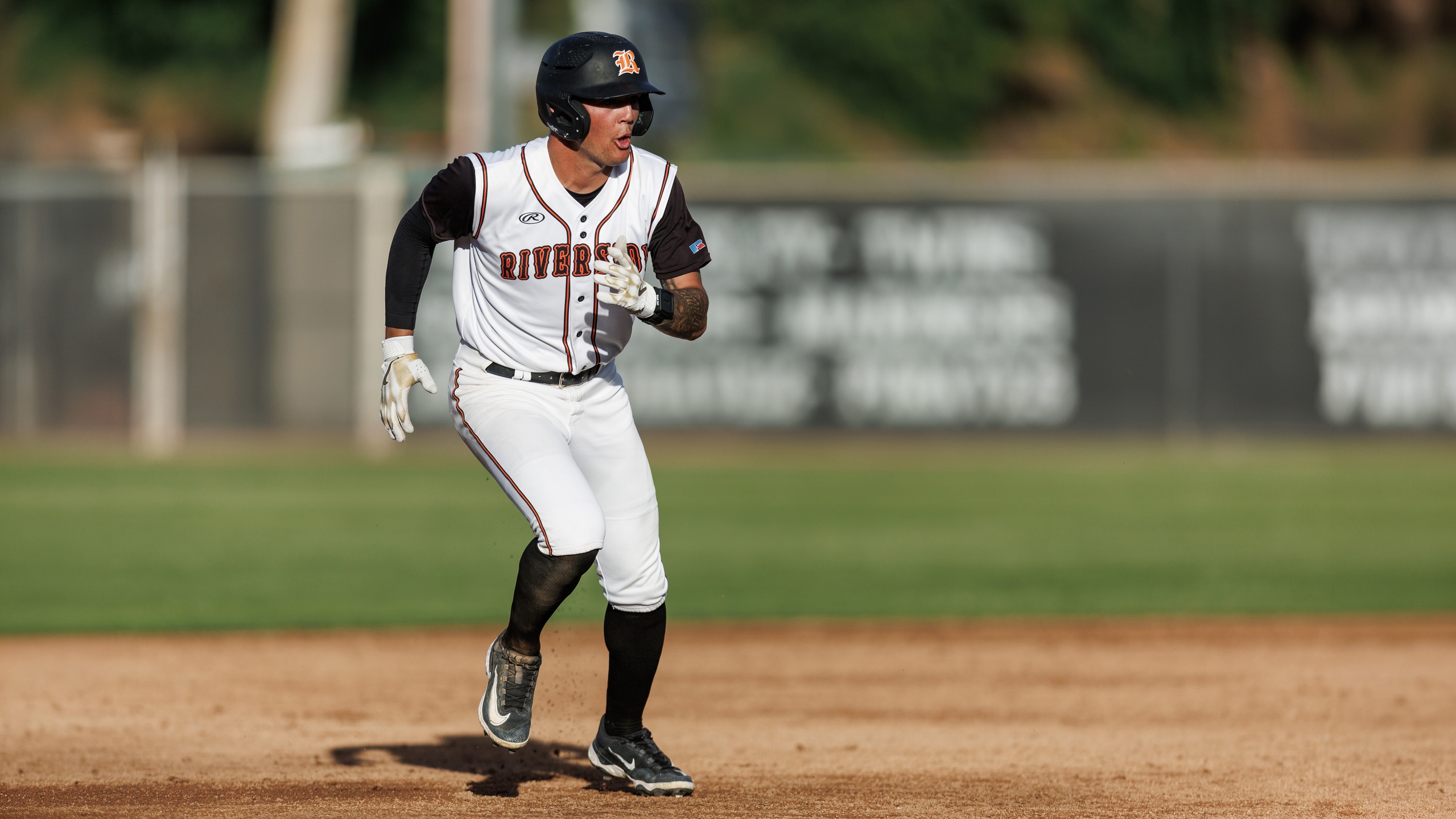 Baseball player in white uniform and black helmet gets ready to run
