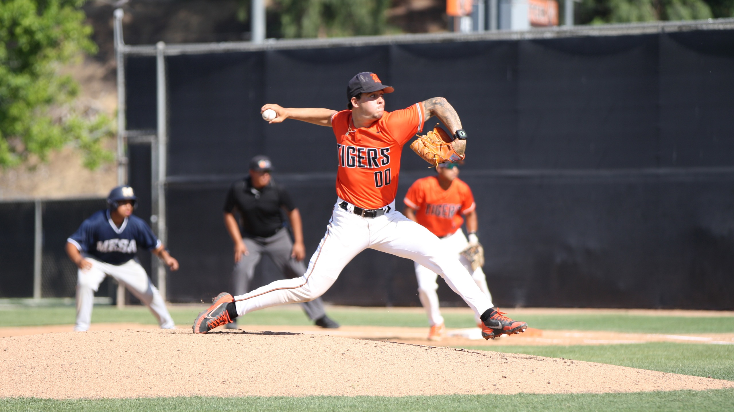 A baseball pitcher in an orange uniform gets ready to throw the ball