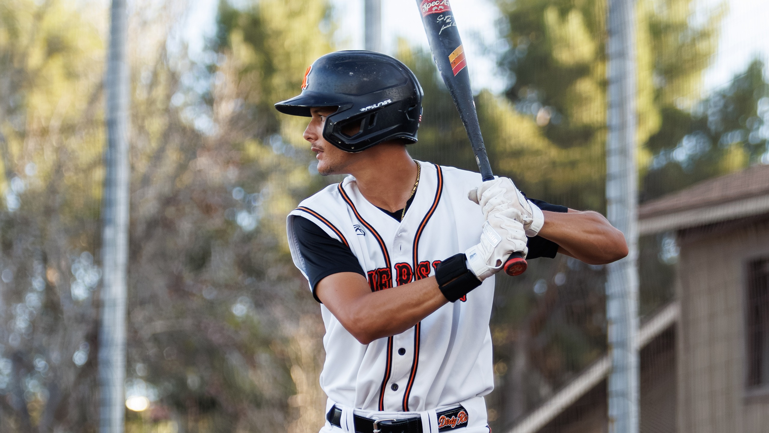 A baseball player in a white uniform gets ready to hit the ball