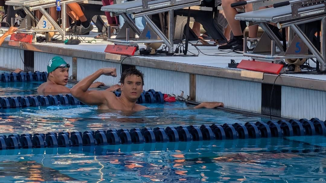 Swimmer flexes his muscle after finishing a race