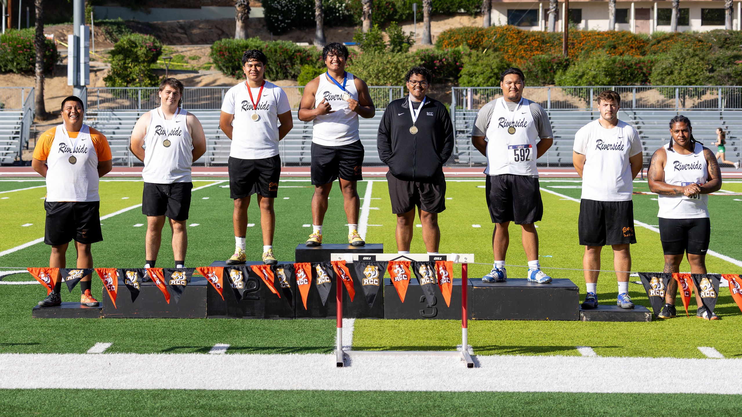 Eight men on podium for shot put championship, smiling with medals