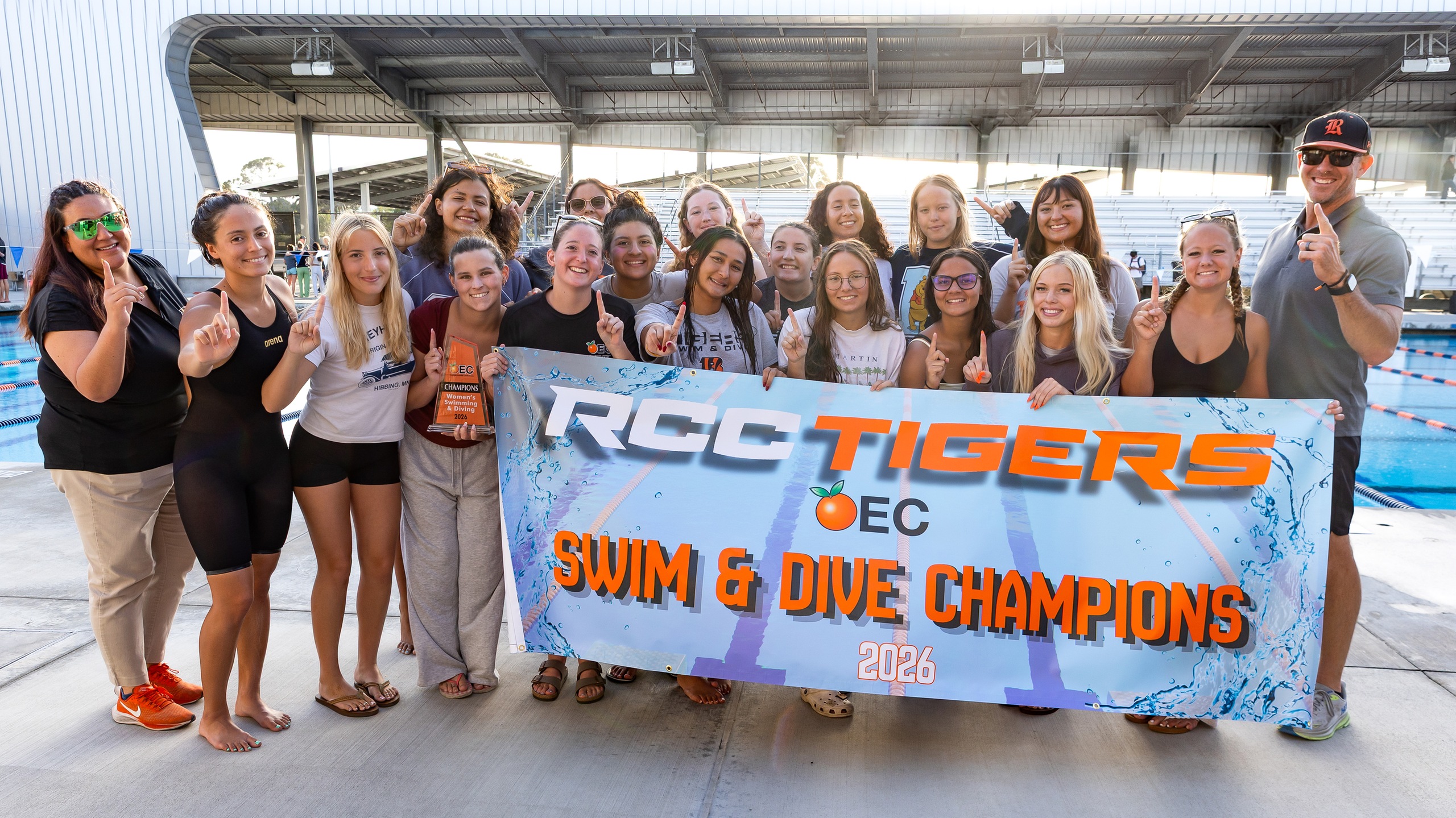 The RCC women's swim and dive team poses with a banner that says RCC Tigers OEC Swim & Dive Champions
