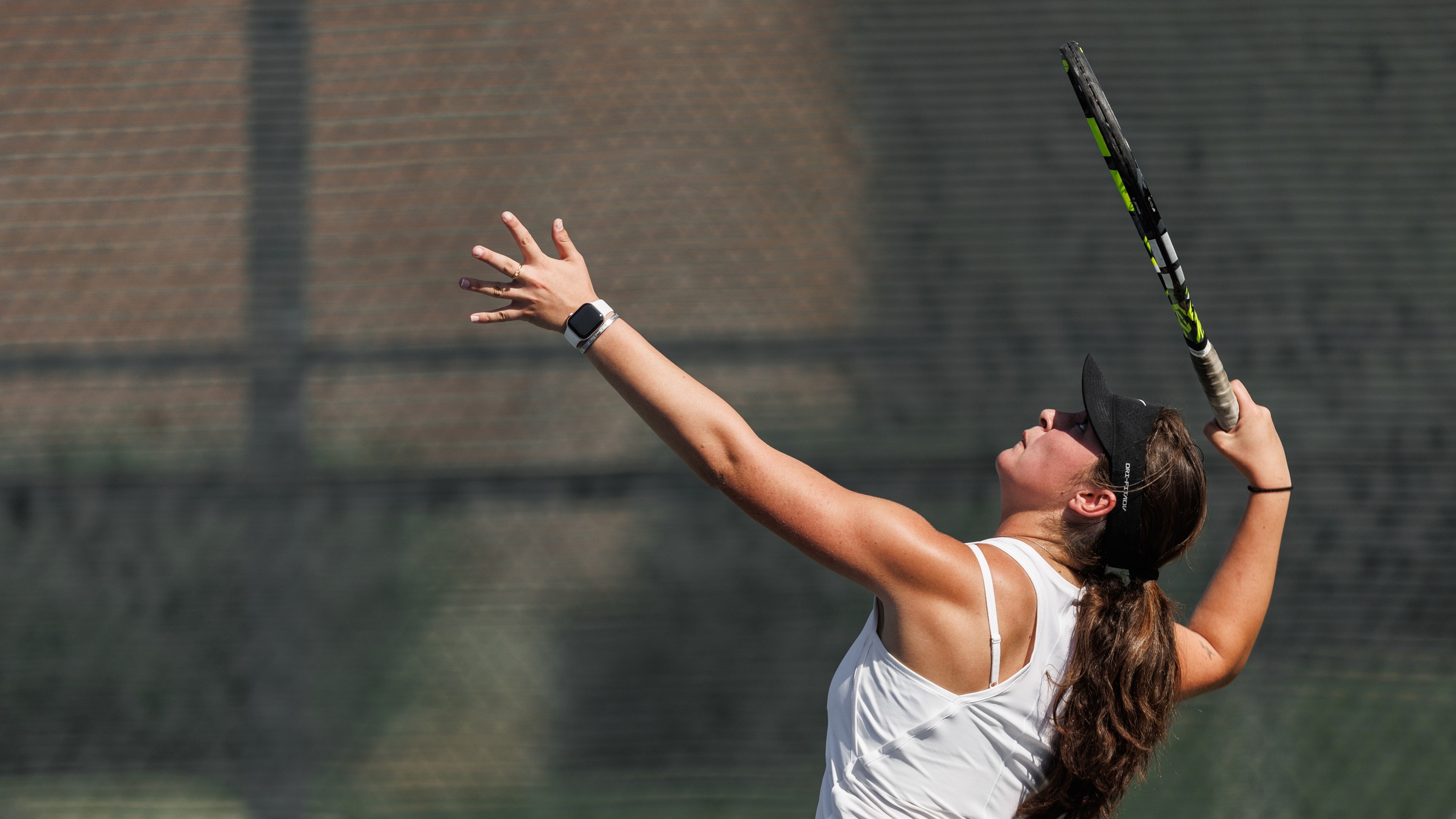 Women's tennis player in white top gets ready to hit the ball