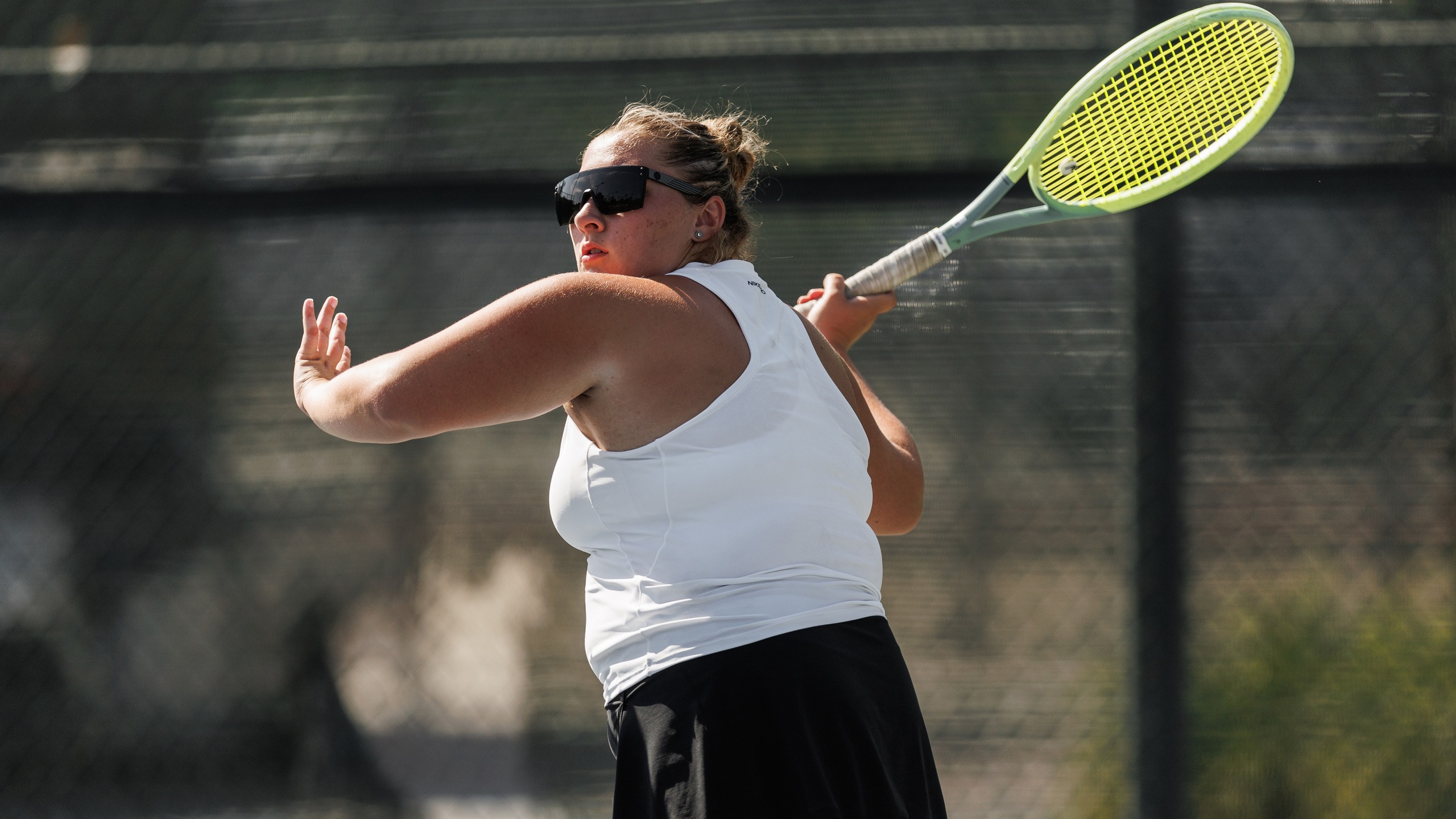 Women's tennis player in white outfit gears up to swing the ball