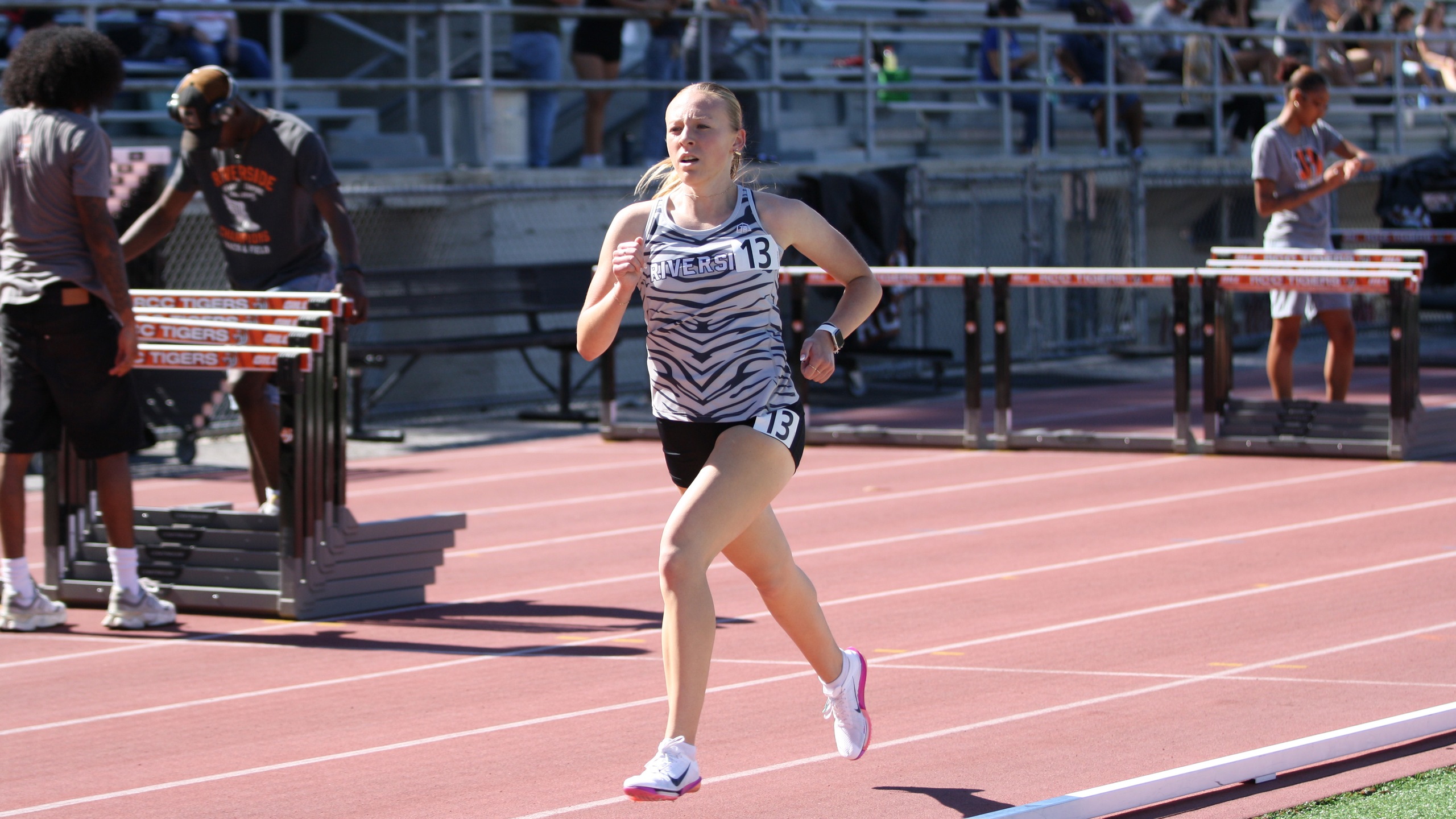 A girl sprinting on a track while a crowd cheers her on from the sidelines.